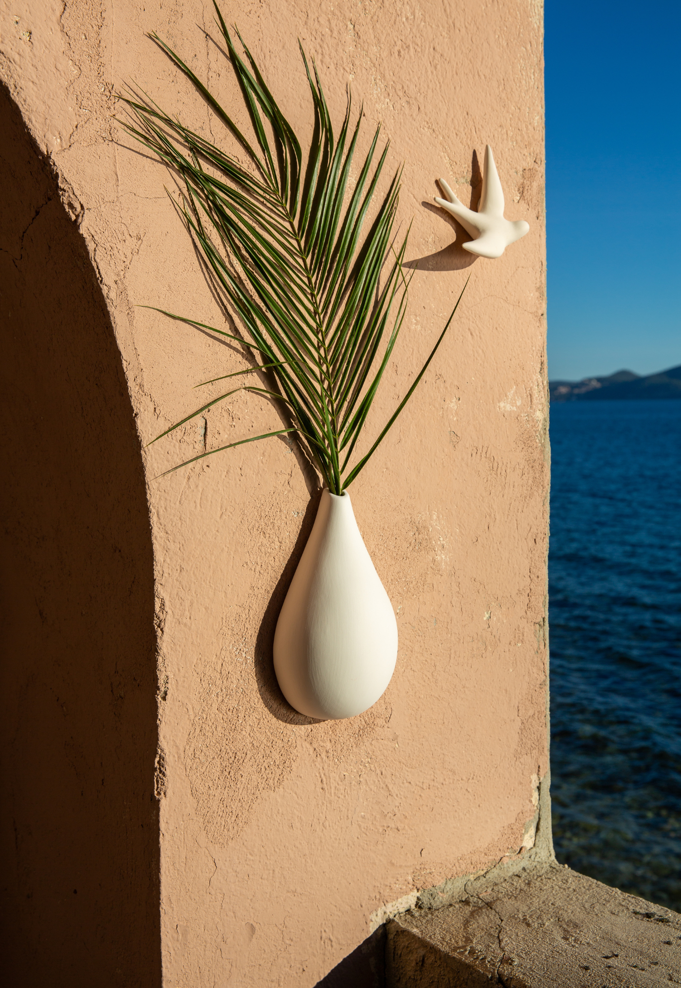 swallow wall décor blanc naturel hanging on wall outside looking towards the ocean