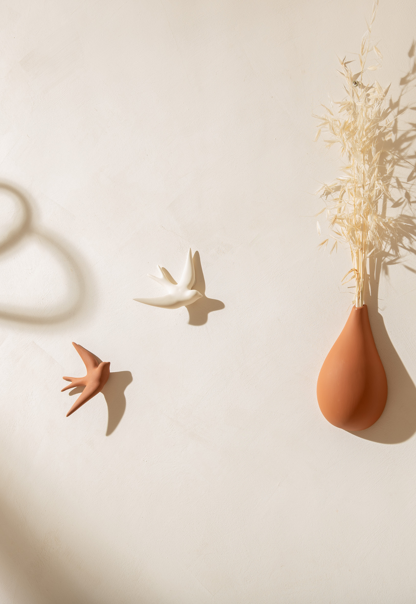 swallow wall décor terracotta hanging on wall in living room setting with neutral tones