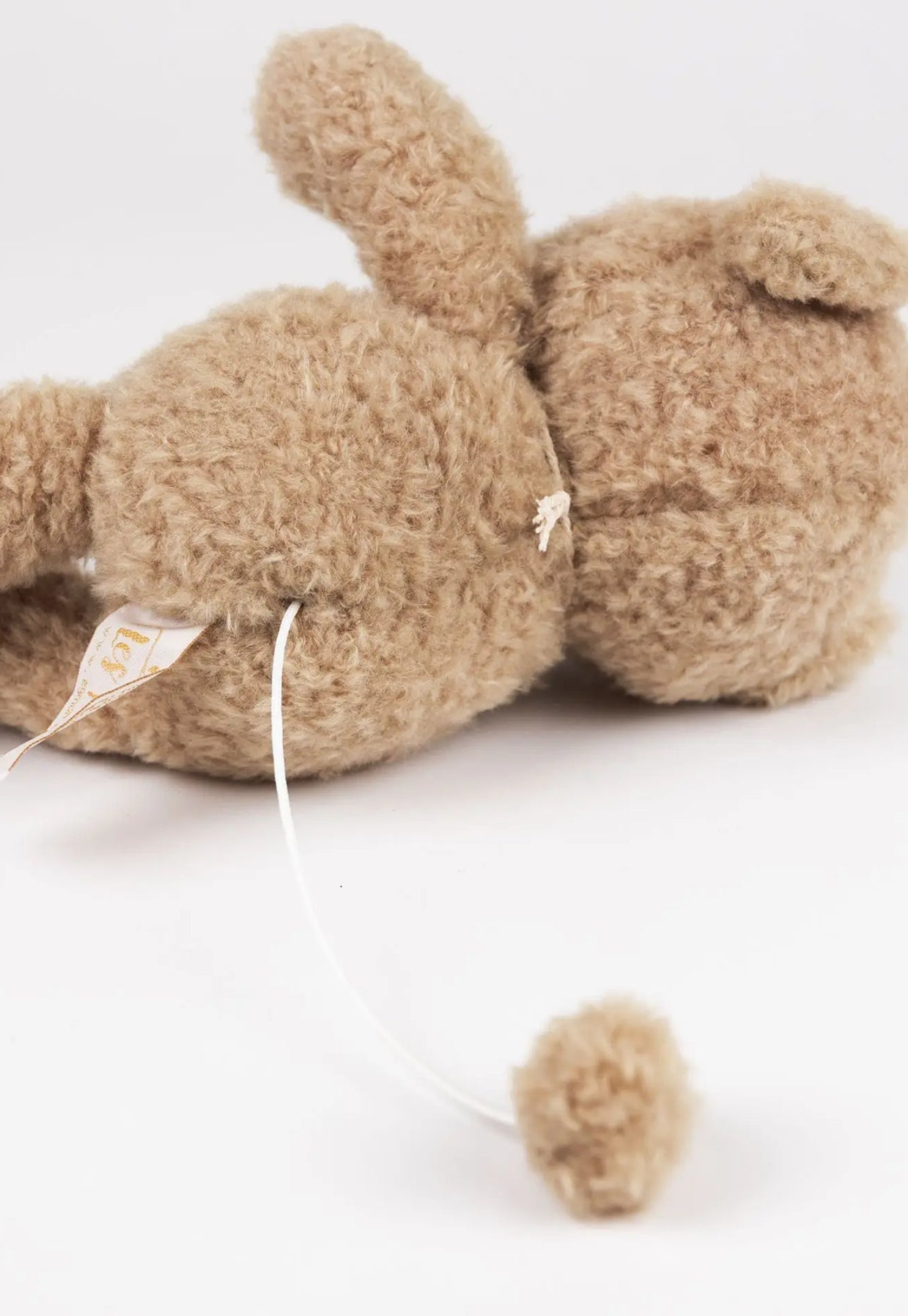 back of close up of morris musical bear showing soft beige plush fur and stitched details